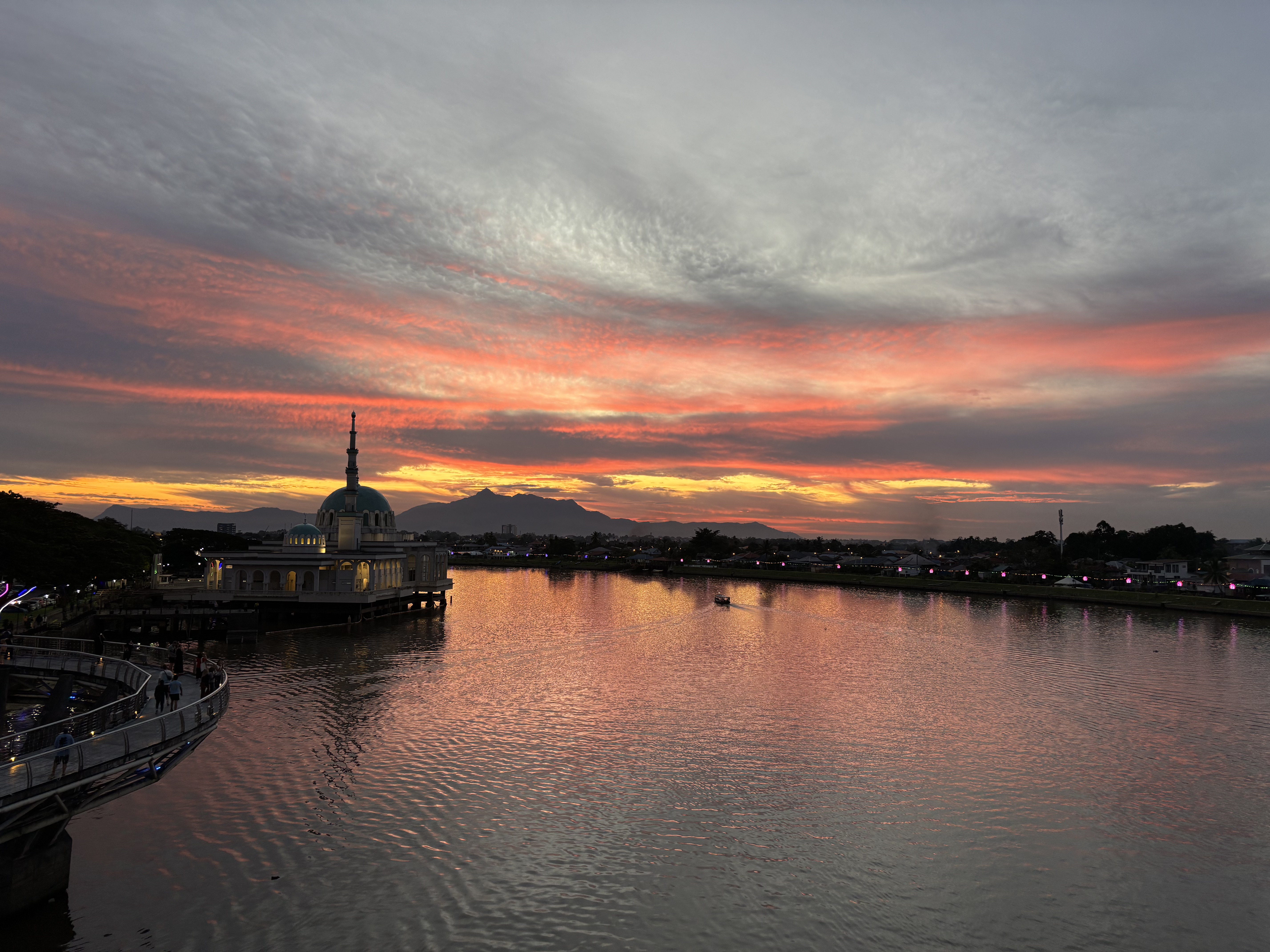Kuching Waterfront al tramonto, con il fiume Sarawak, il Darul Hana Bridge e il cielo illuminato dai colori del tramonto