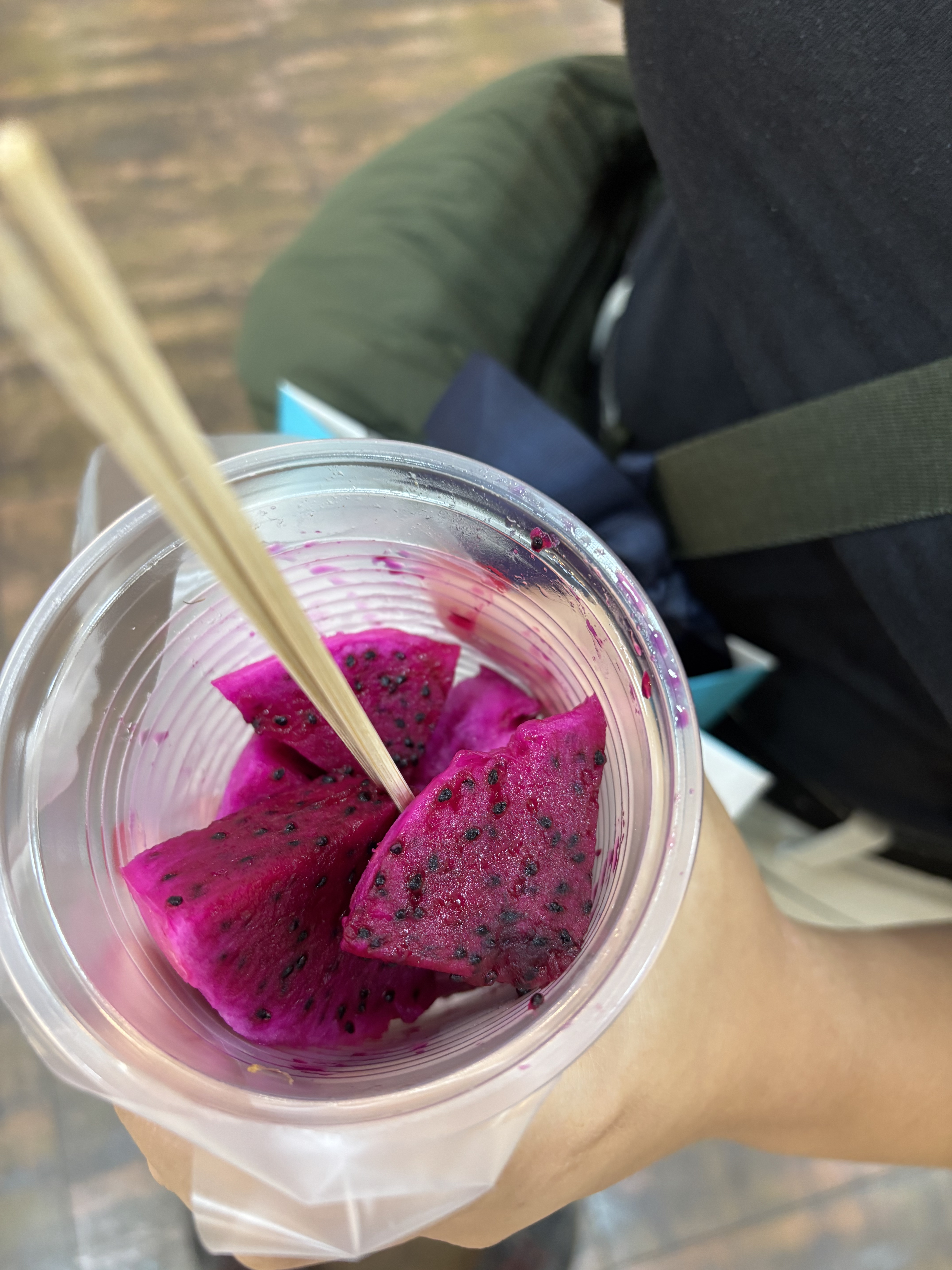 Pezzi di frutto del drago in un bicchiere di plastica tenuto in mano