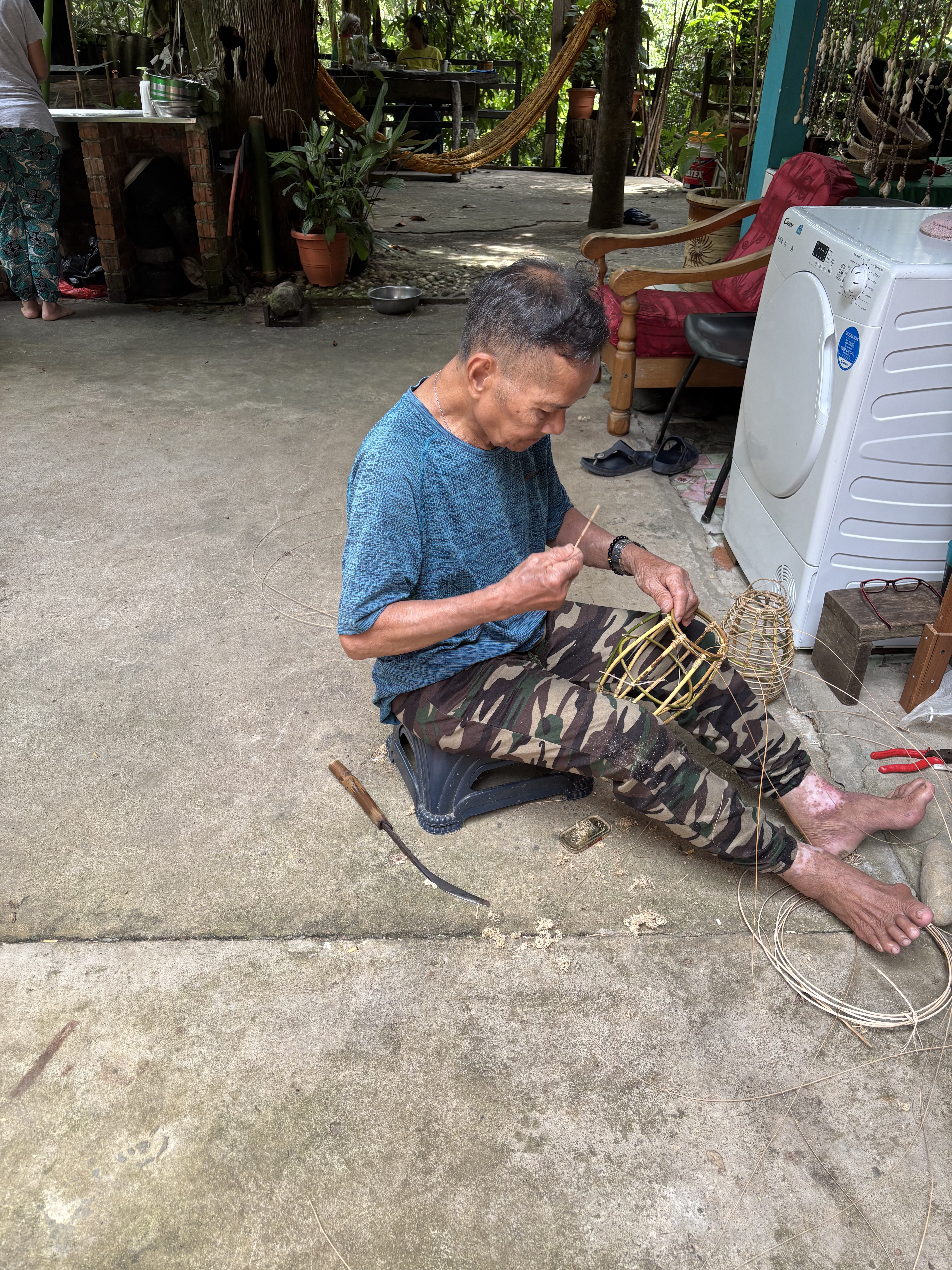 Il padre di Saloma intento a intrecciare un cesto in rattan nel cortile del Saloma Villagestay