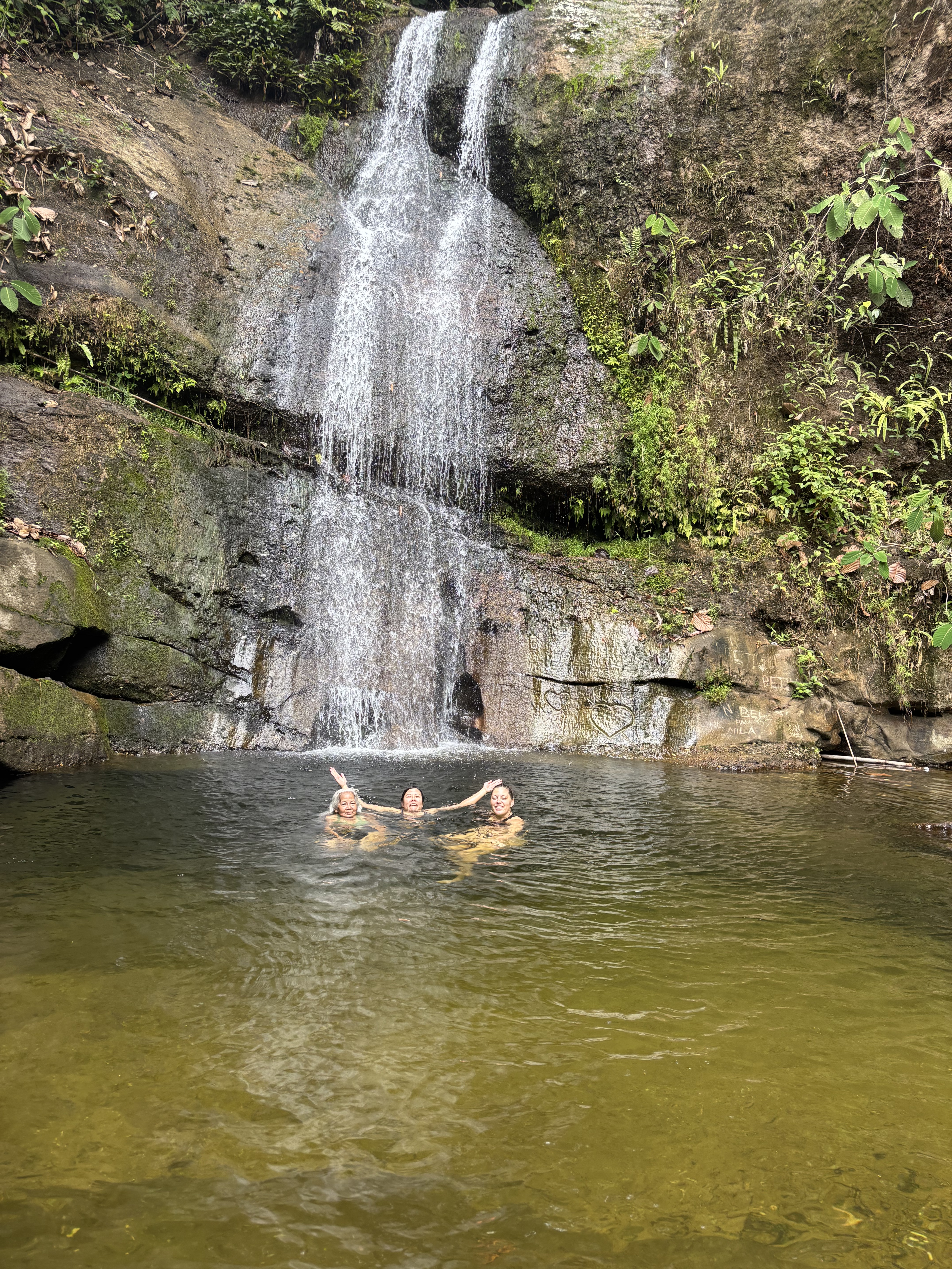 Cascata nella foresta del Sarawak con persone immerse nella piscina naturale